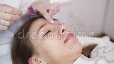 在工作室美容师眉毛治疗期间躺在沙发上的女孩，美容师在美容院脱毛和眉毛整形